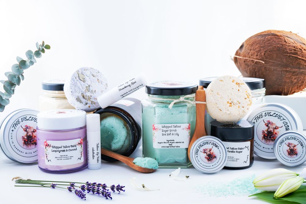 Aromatherapy products including candles, bath salts, and body butters displayed with coconuts and lavender sprigs on blue surface.