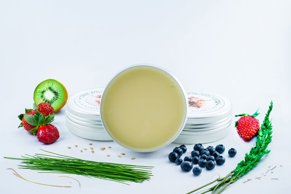 Fresh berries, herbs, and white dishes arranged with a bowl of pale soup on a light background.