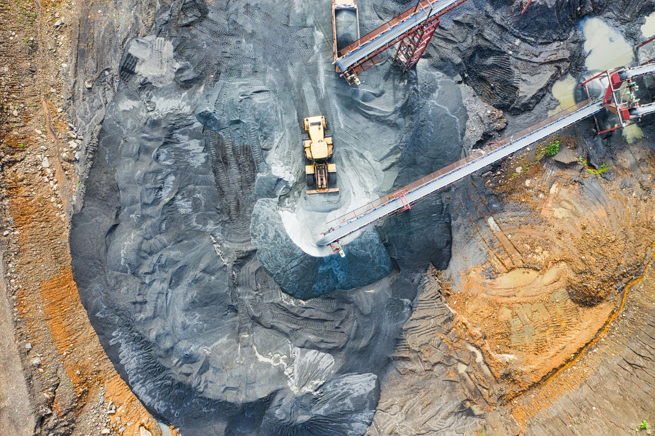 Aerial view of mining operations with excavators working in dark terrain.