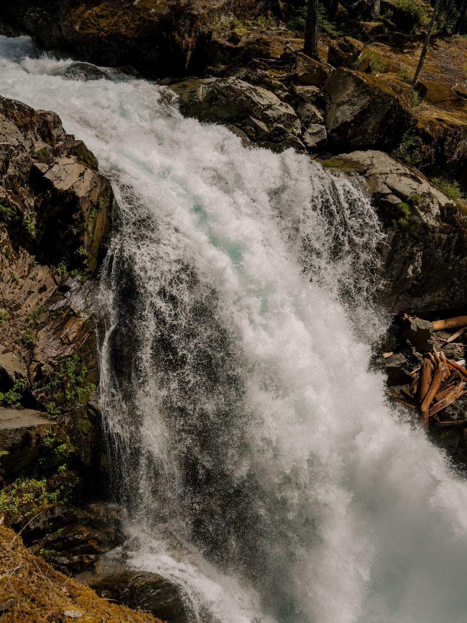 Powerful waterfall cascading over rugged rocks with white rushing water in a natural forest setting.
