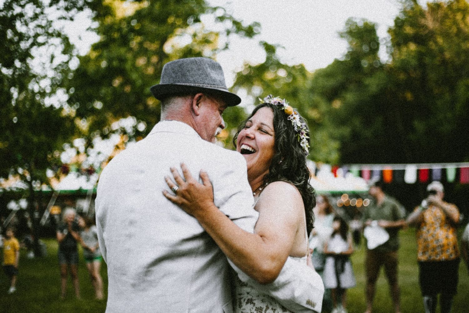 A joyful candid moment of a couple dancing at an outdoor garden wedding celebration.
