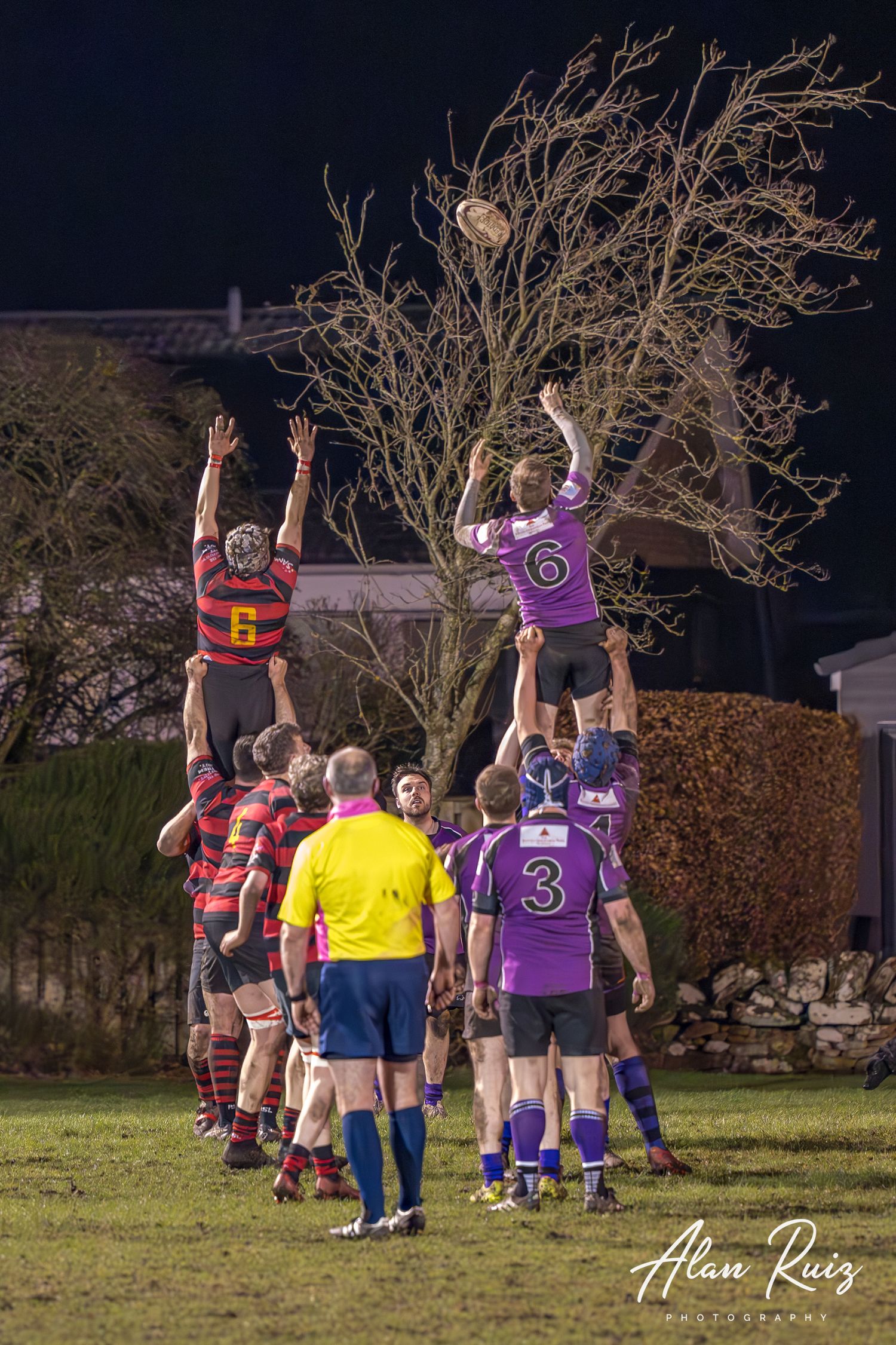 Rugby players execute a lineout play with teammates lifting jumpers to catch the ball.