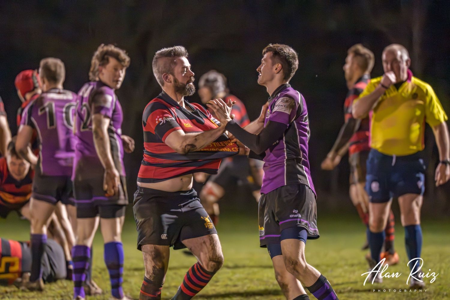 Rugby players from opposing teams clash during an intense play on the field.