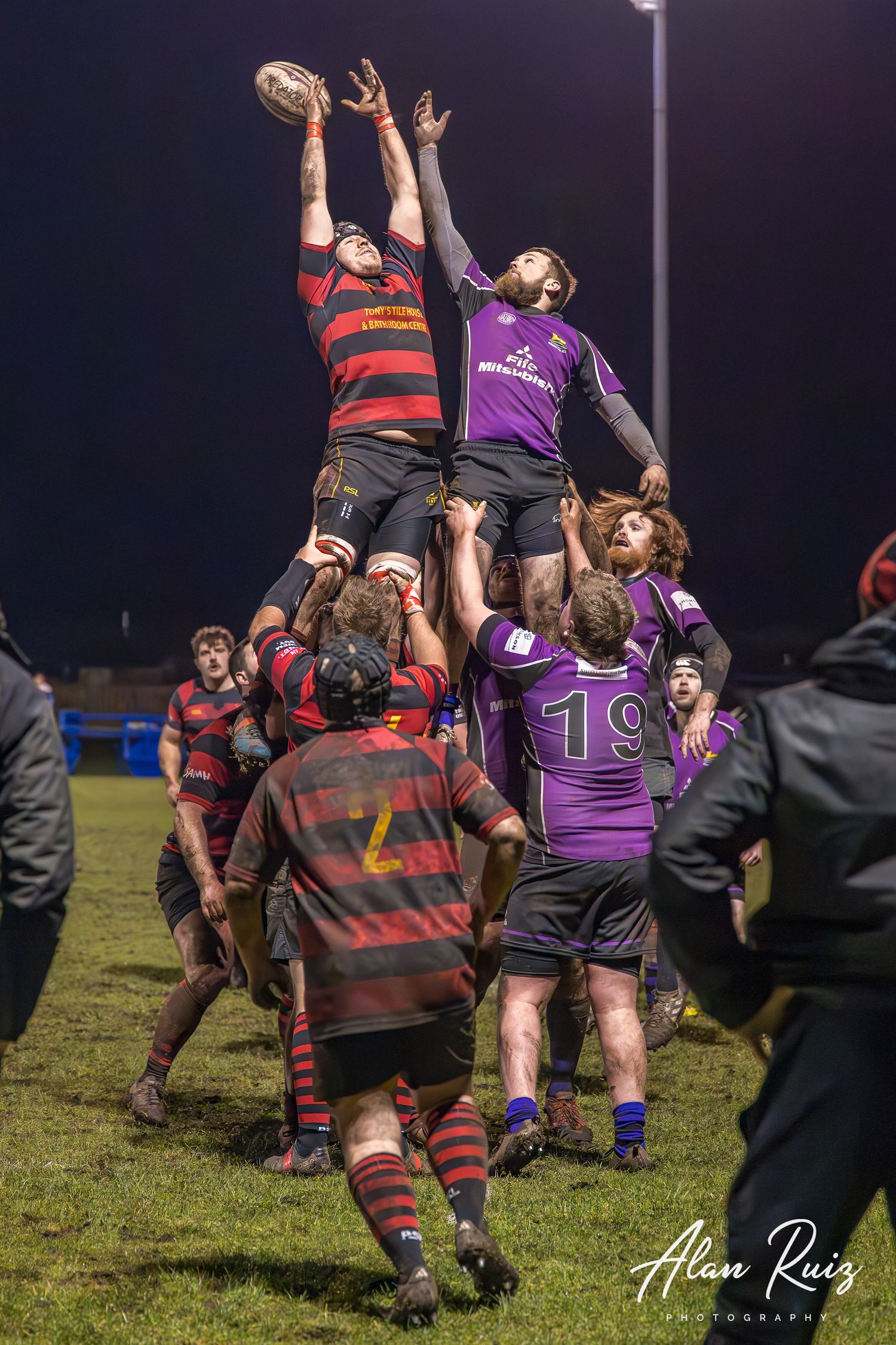 Rugby players compete for possession during a lineout play with one player being lifted by teammates.