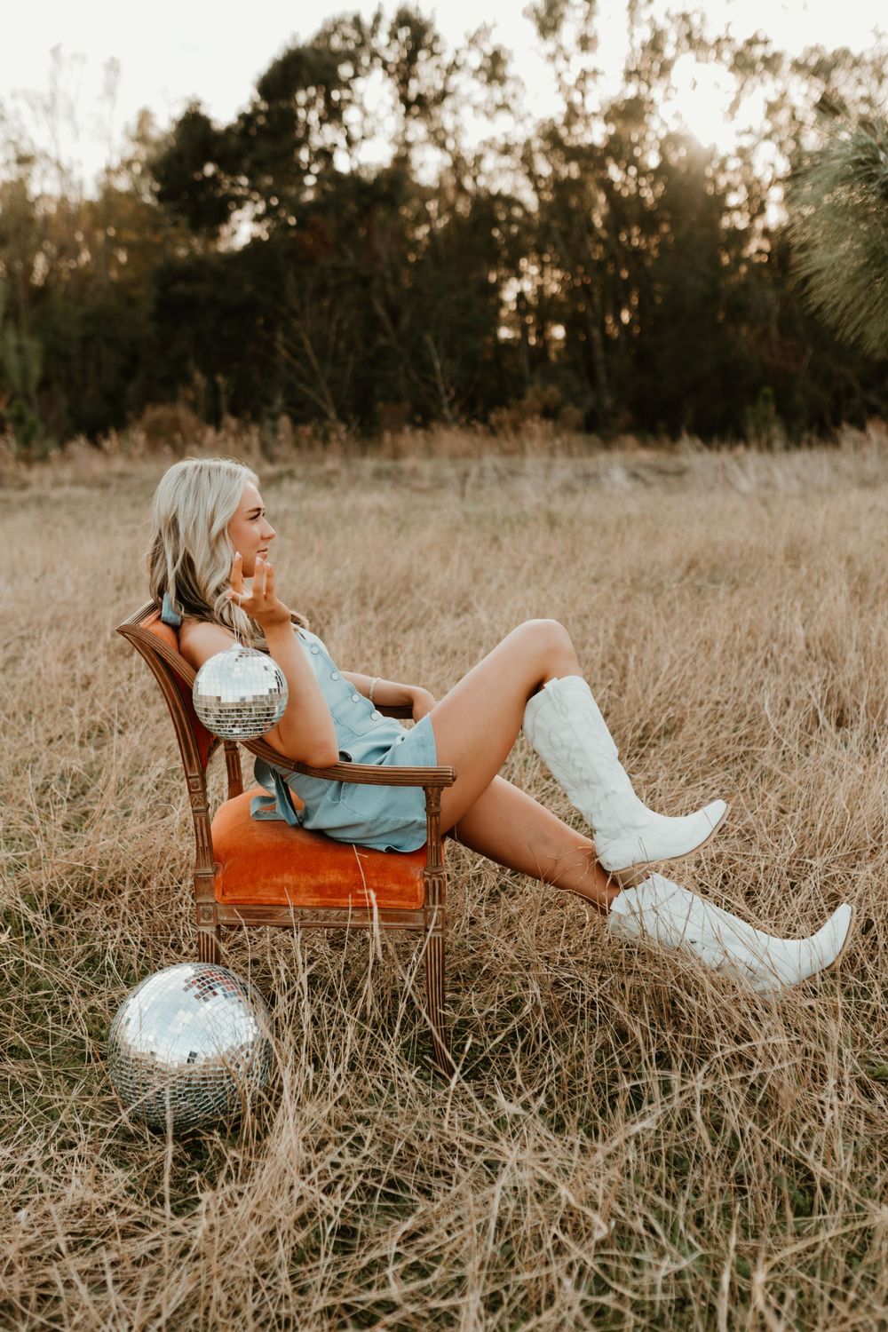 Retro styled portrait with disco balls and orange chair in golden field setting.