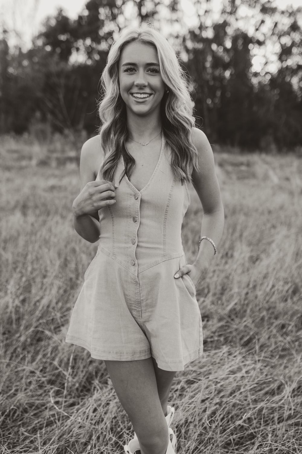 Person in beige outfit poses candidly in field during outdoor photoshoot.