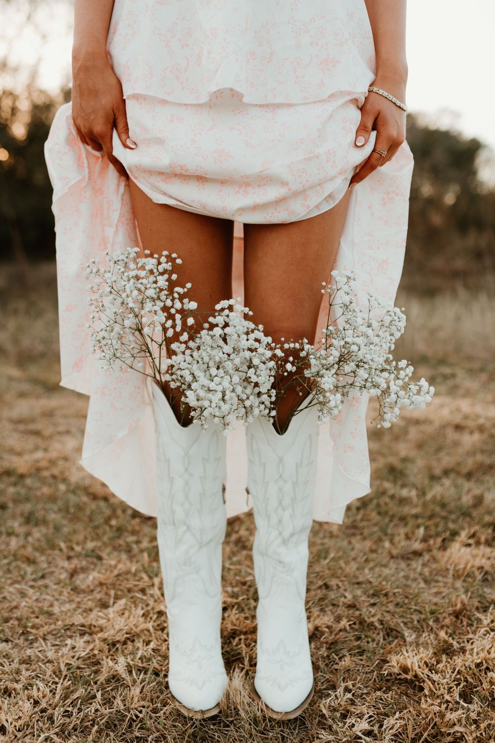 White boots and baby's breath flowers detail shot against dried grass.