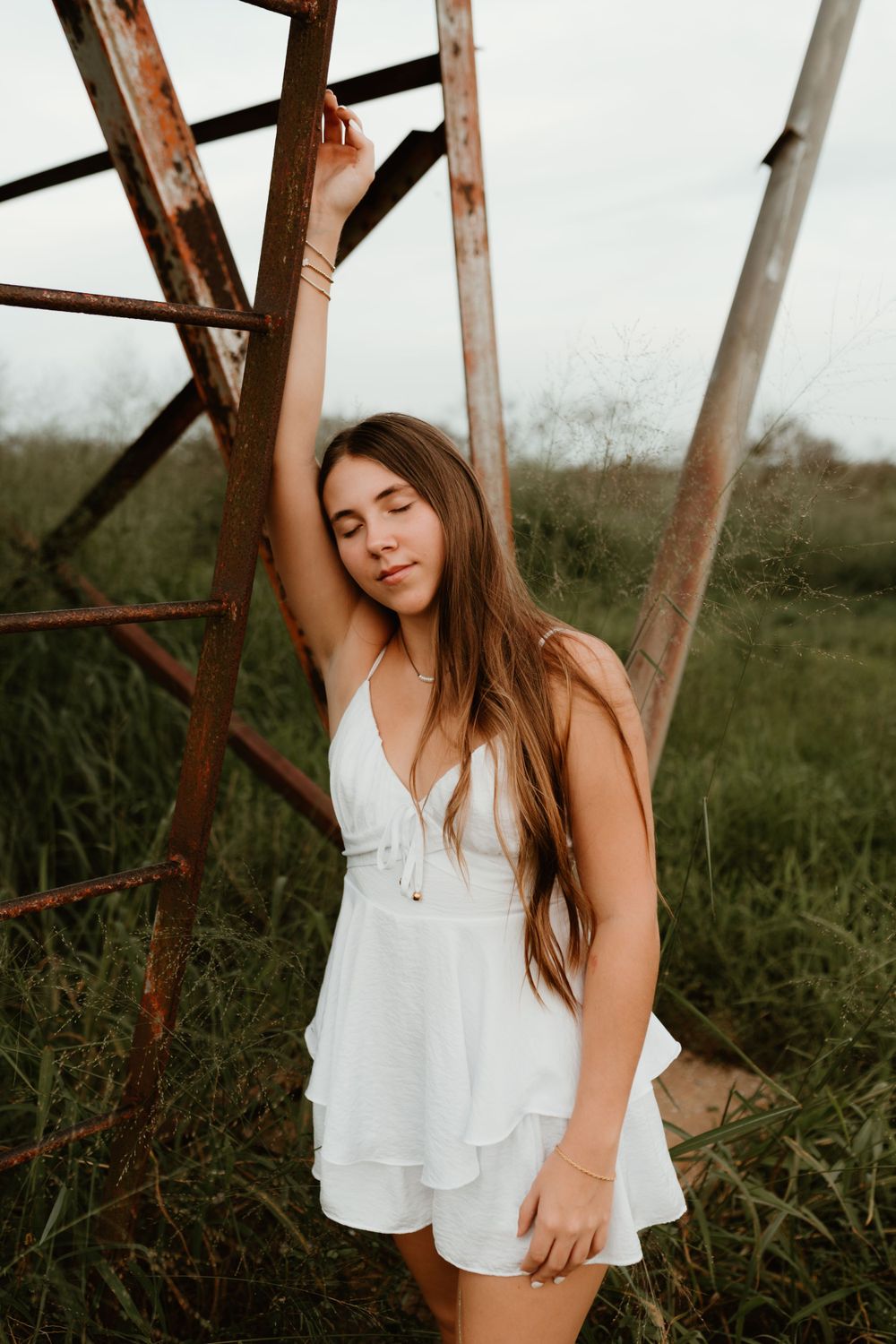 Artistic outdoor portrait sequence showing someone in a white top posing against rustic metal structure in a field.