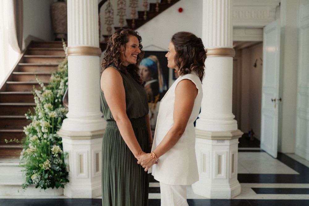 A couple holds hands while standing between elegant white columns during their special day.