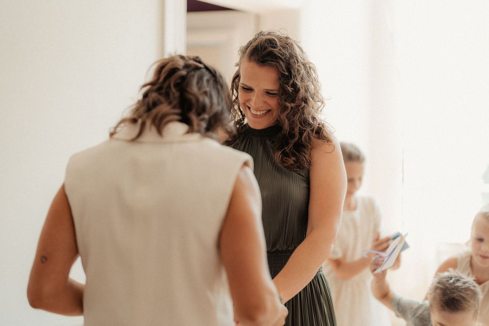 Two people share a tender moment during a wedding celebration in an indoor setting filled with warm lighting.