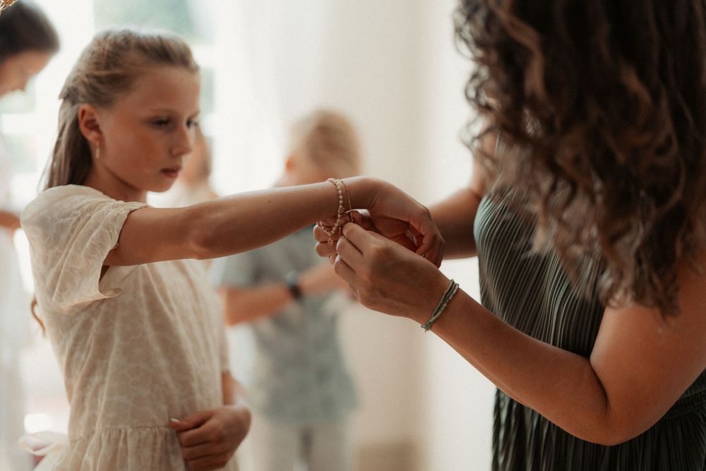 A child in a white dress holds hands with an adult during what appears to be a dance class or lesson.