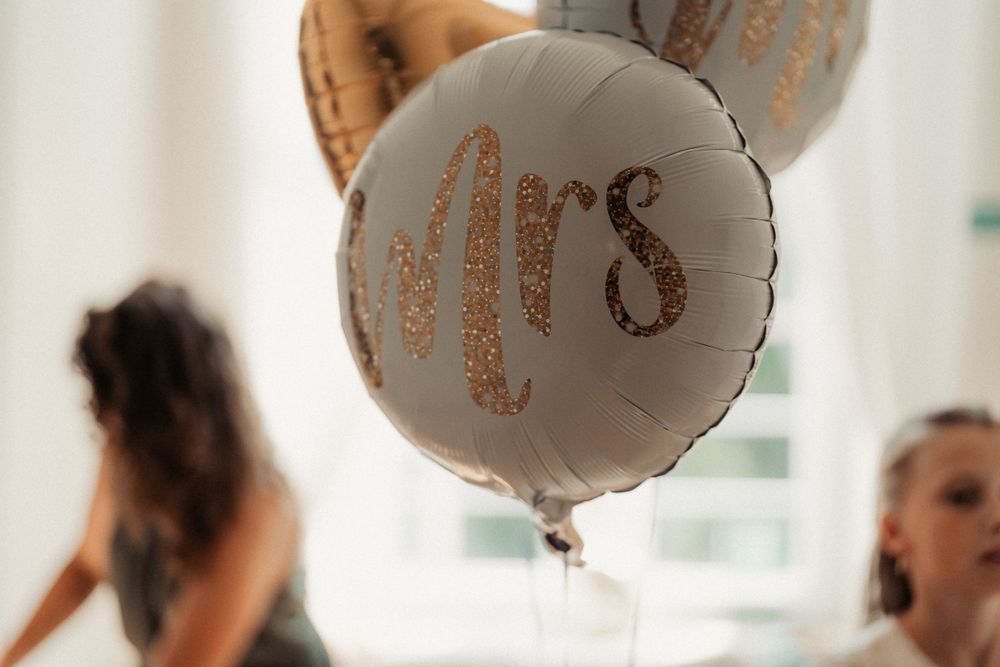 A silver Mrs balloon floats in a bright indoor space during a wedding celebration.