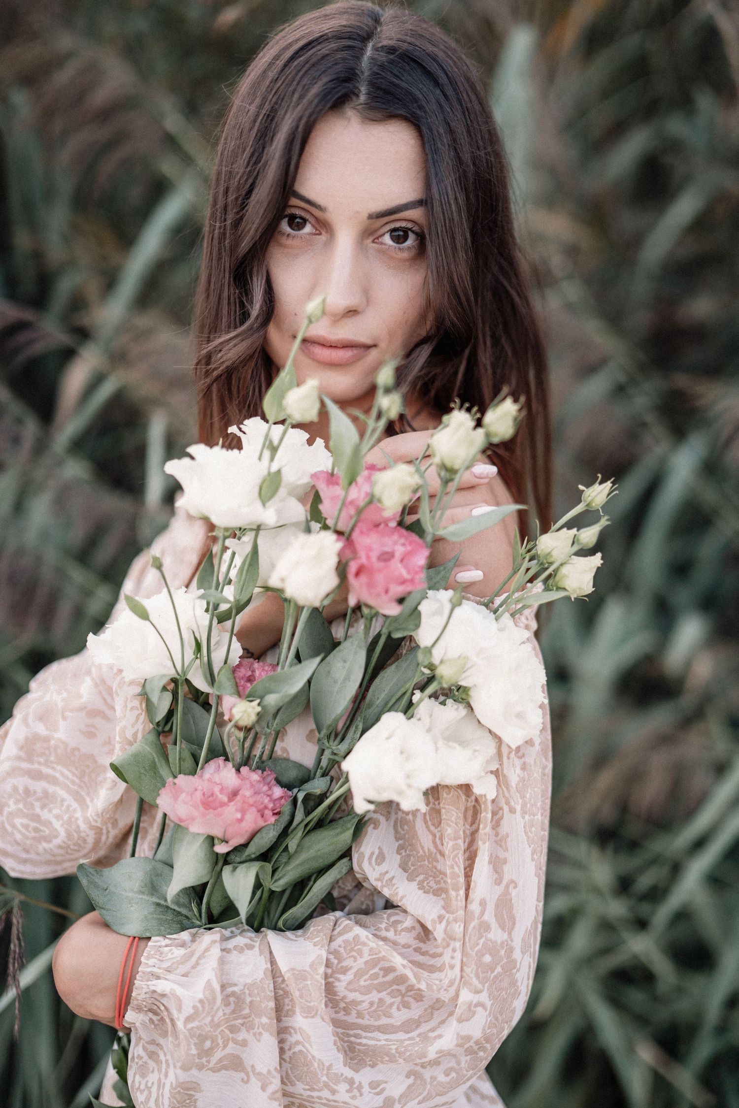 Person holding elegant bouquet of pink and white roses in romantic setting.
