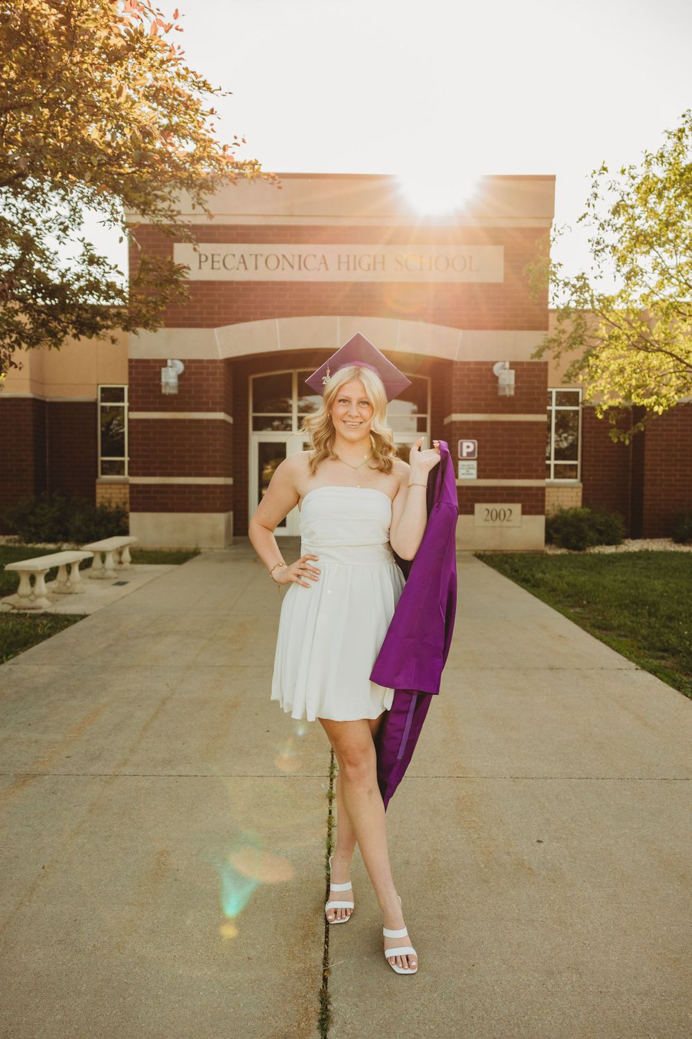 Playful graduation portraits at sunset showing movement in purple graduation gown.