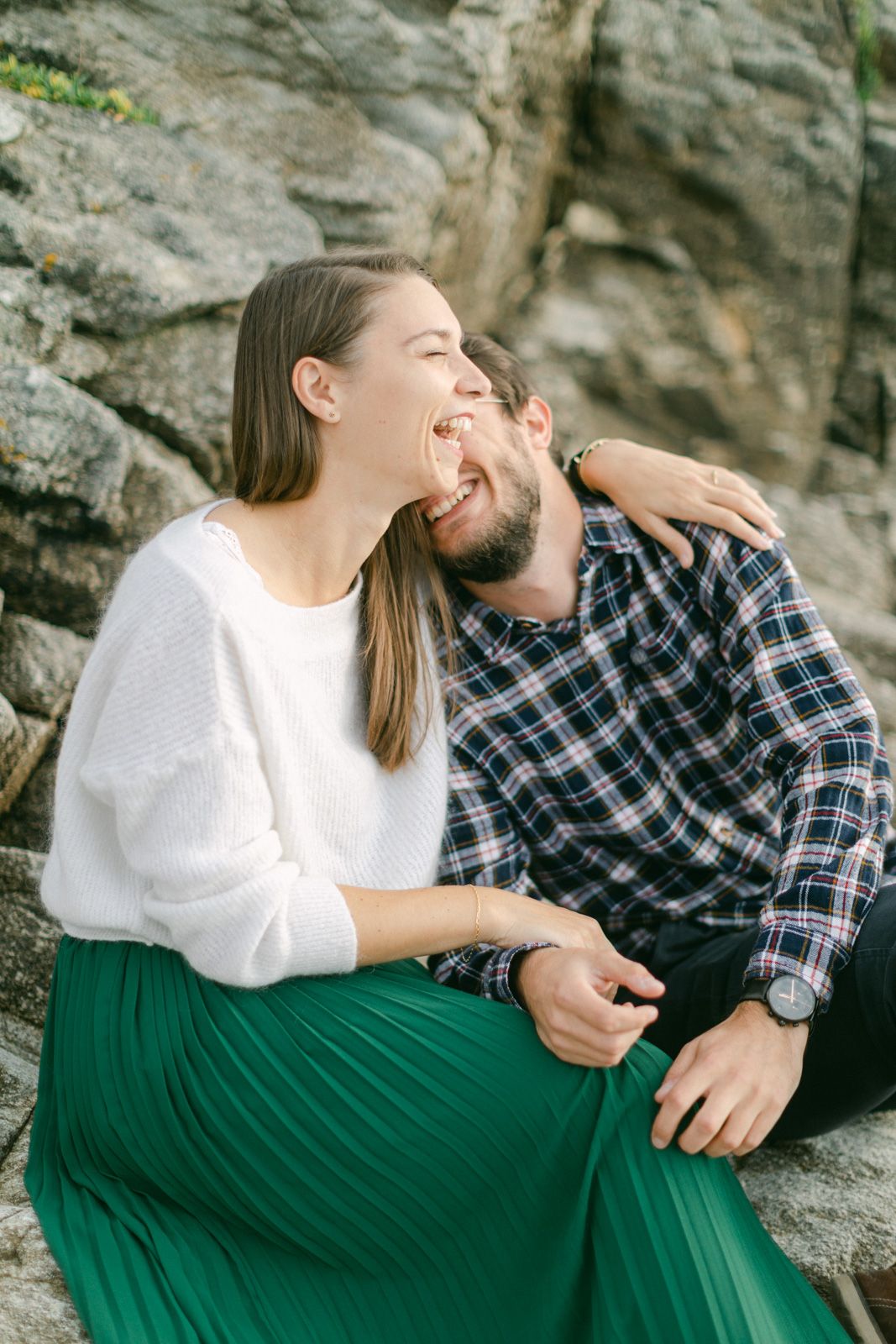 Séance photo couple à Nantes, un moment complice et naturel sur les rochers au bord de l’océan, capturé dans un style lumineux et élégant.