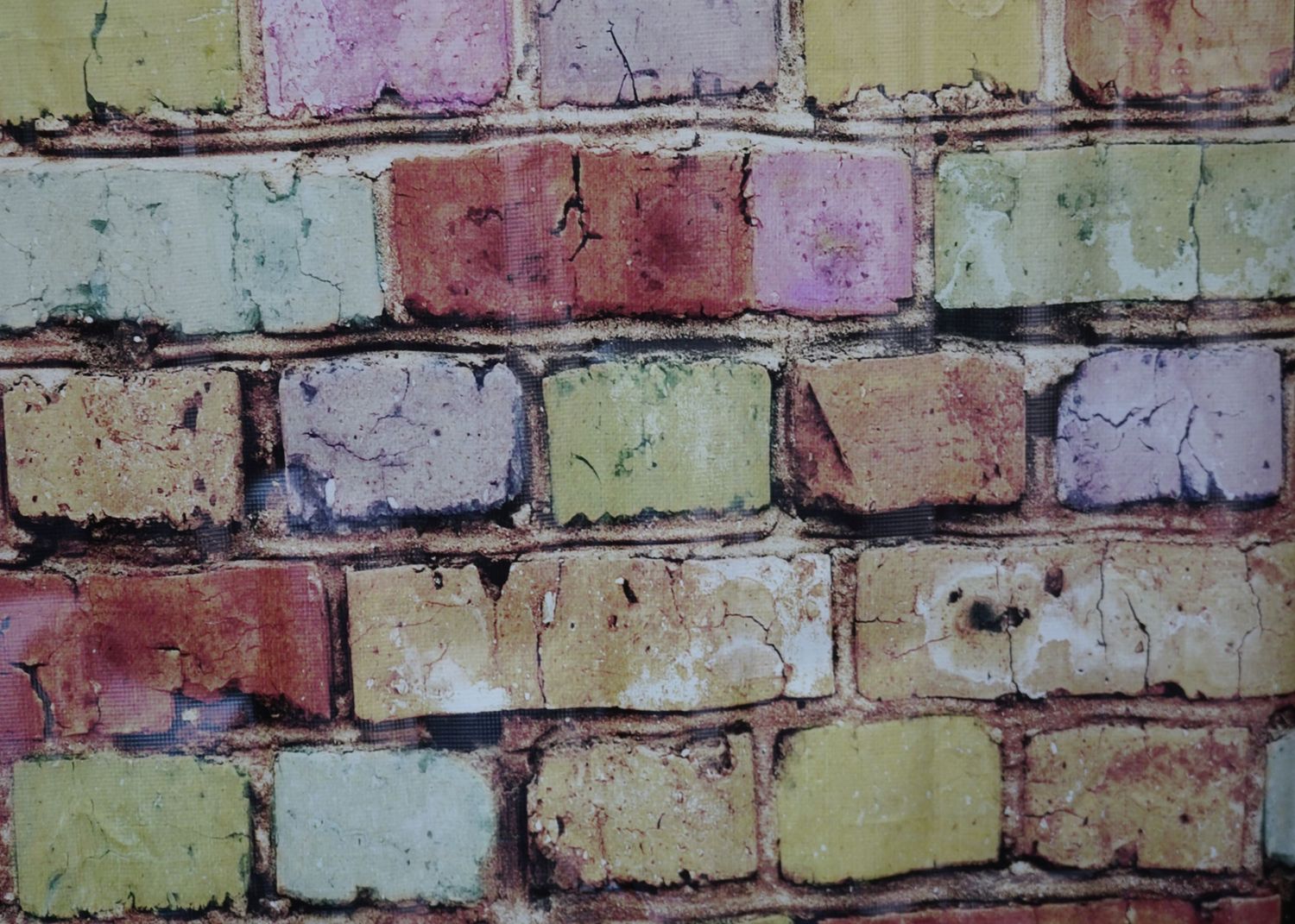 Weathered brick wall texture in pastel yellow and pink tones.