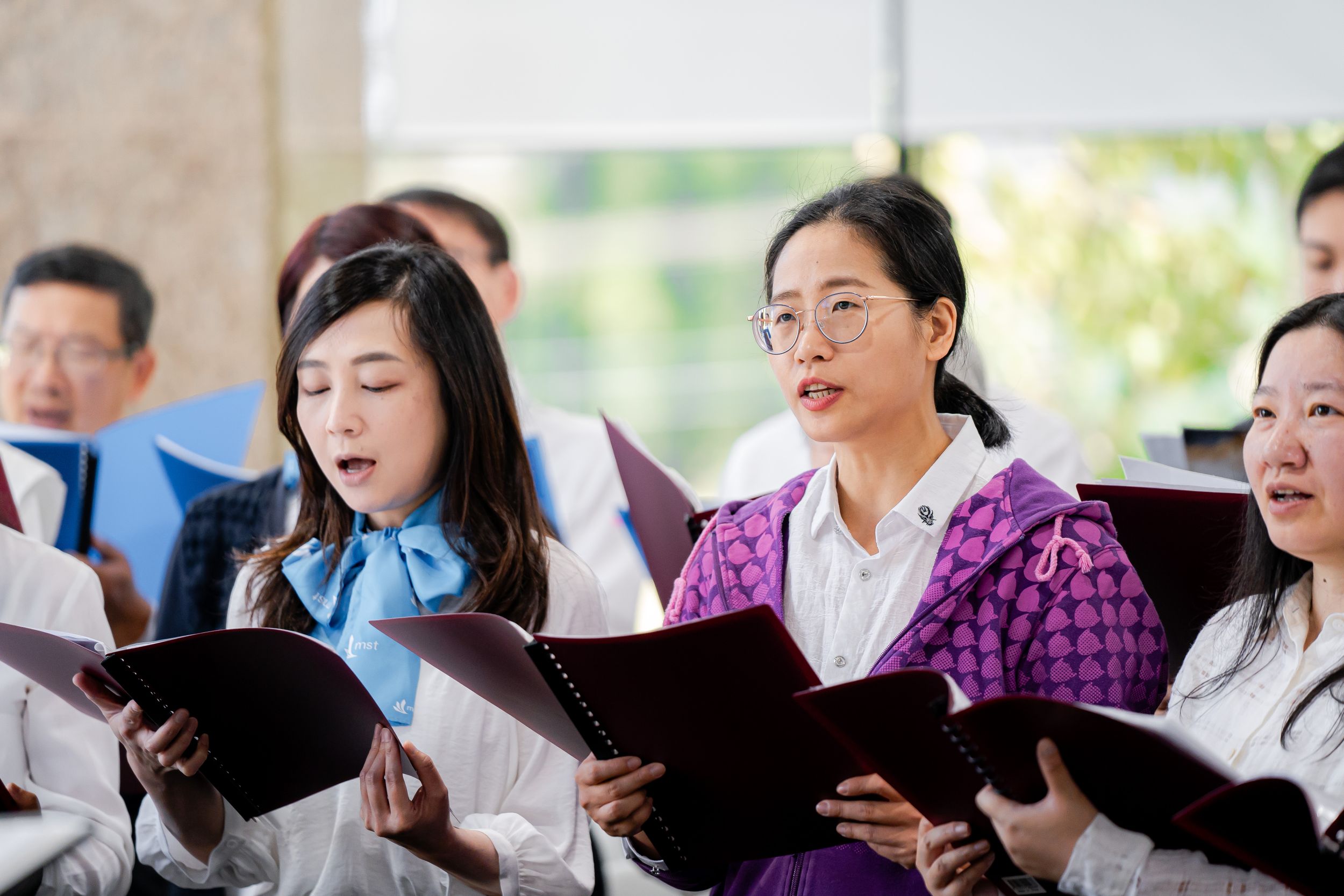 Choir members holding songbooks perform during formal ceremony.