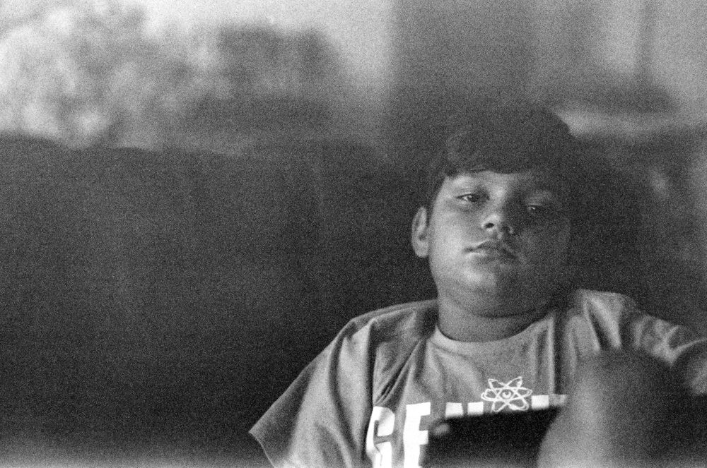 A black and white portrait showing someone resting in moody lighting.