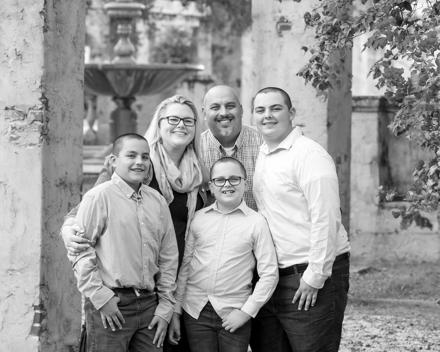 Black and white outdoor portrait of five people posing together near a tree.