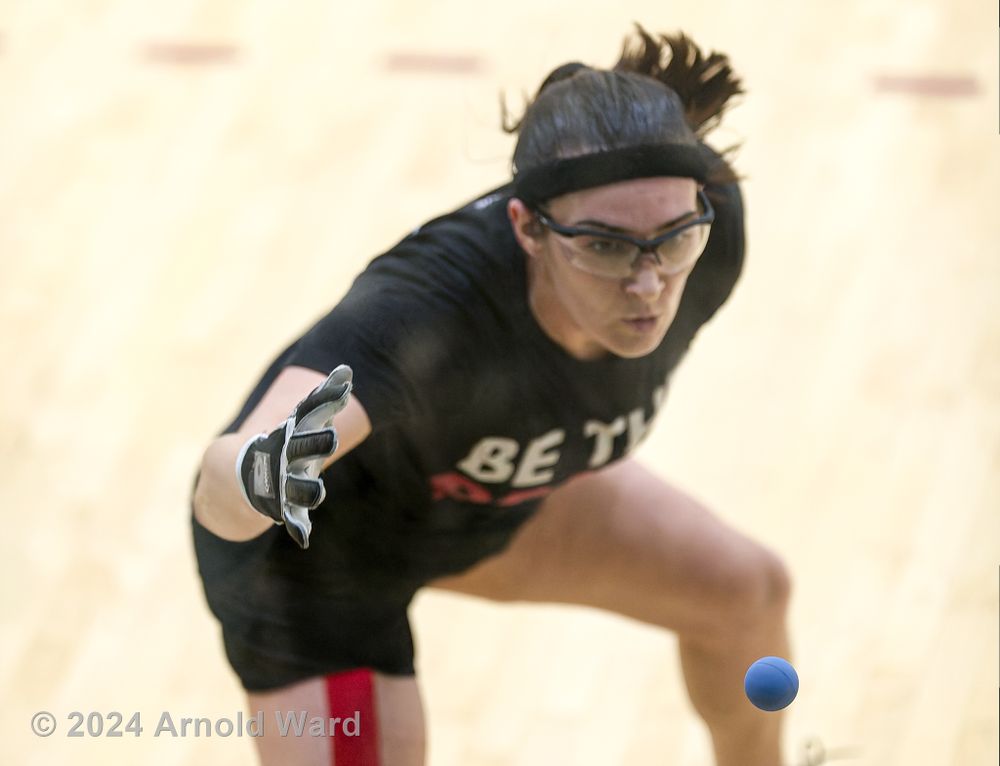 Handball player in black athletic wear lunges forward to make a return shot.