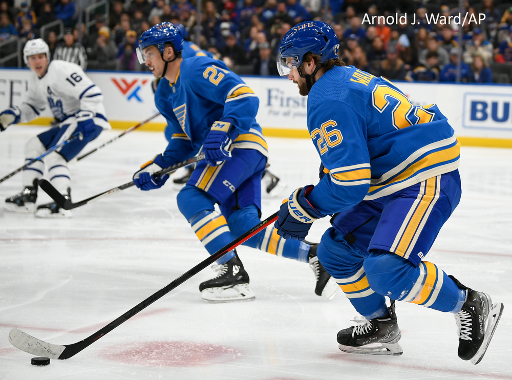 St. Louis Blues hockey players in blue and white jerseys compete for the puck during an intense game.