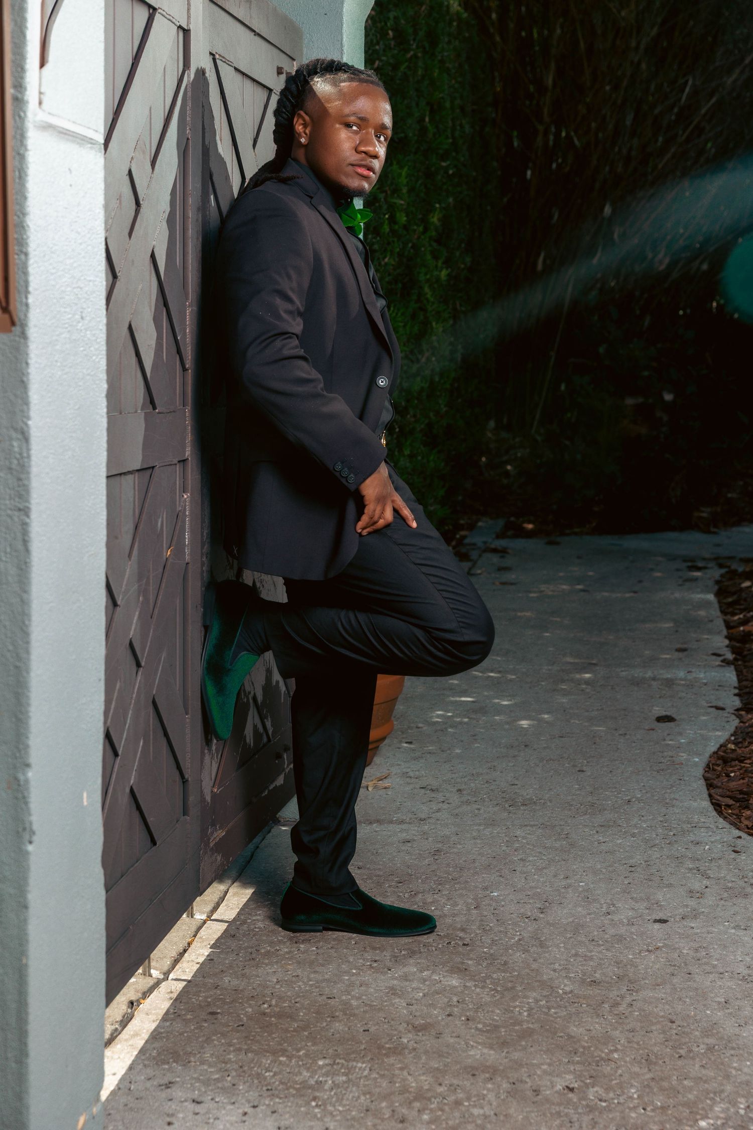 Fashionable Black man in dark blazer poses against wooden gate in dramatic outdoor evening portrait photo.