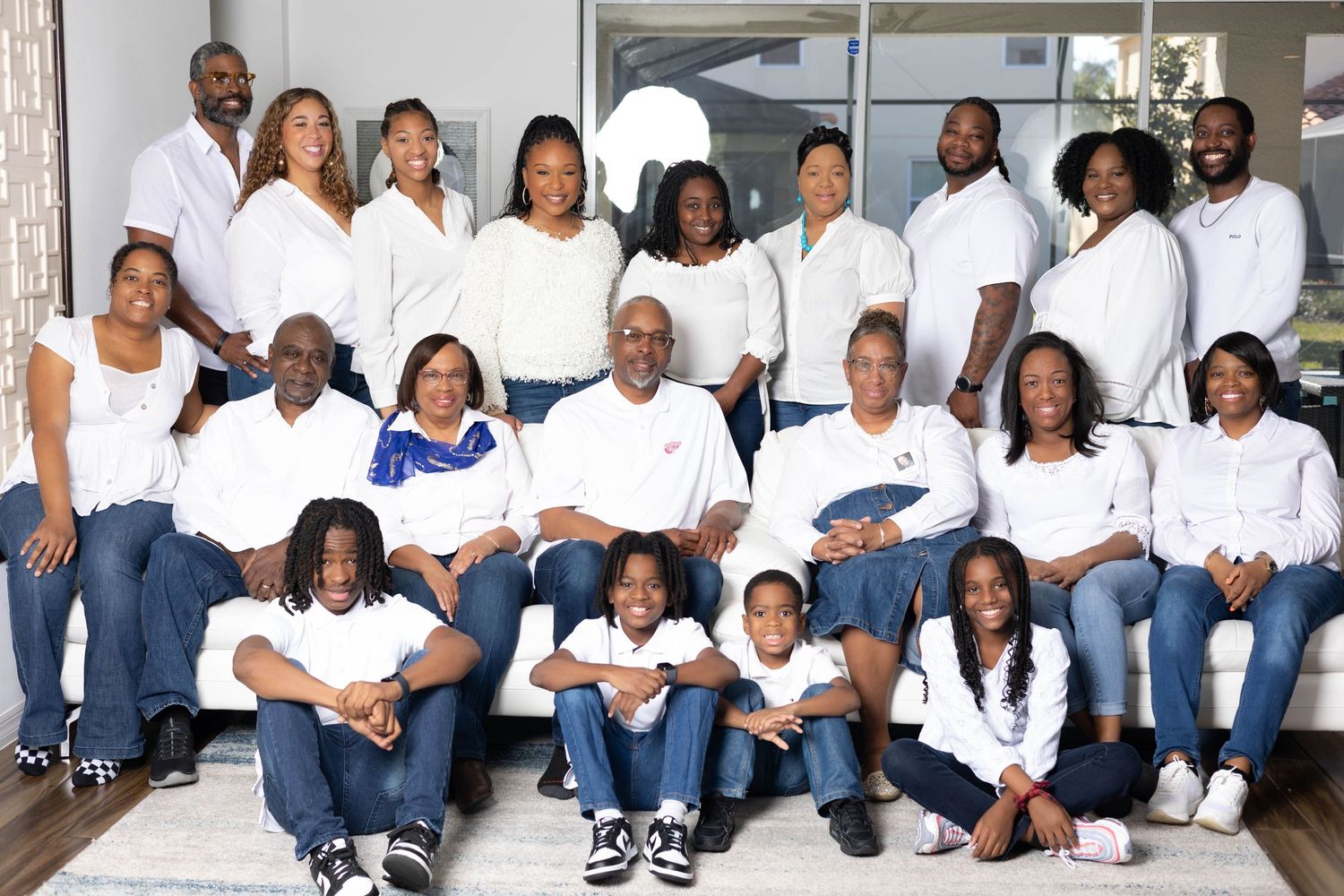 Large family group photo with adults and children in matching white tops and jeans.