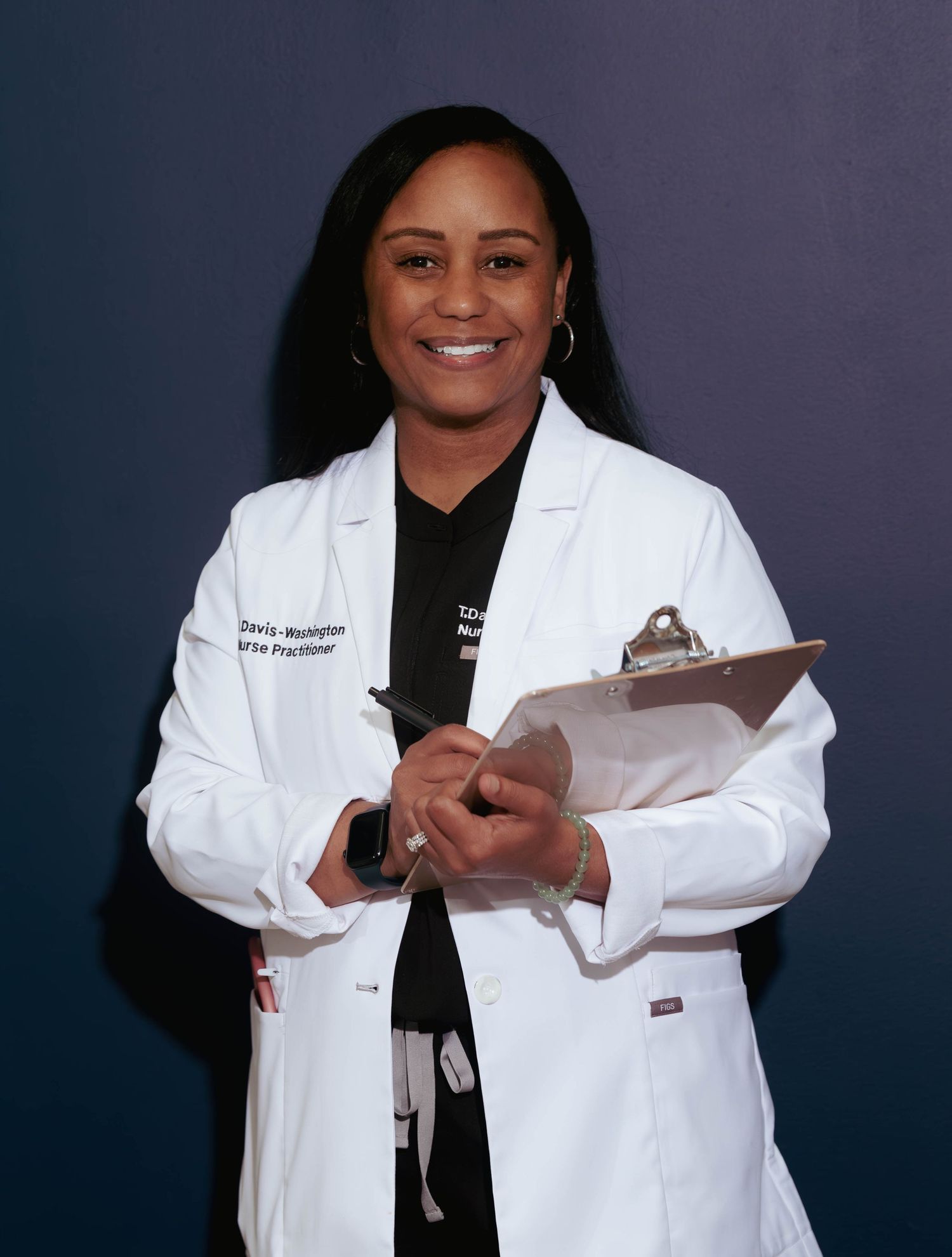 Black female nurse practitioner in white lab coat holding clipboard smiling at camera.