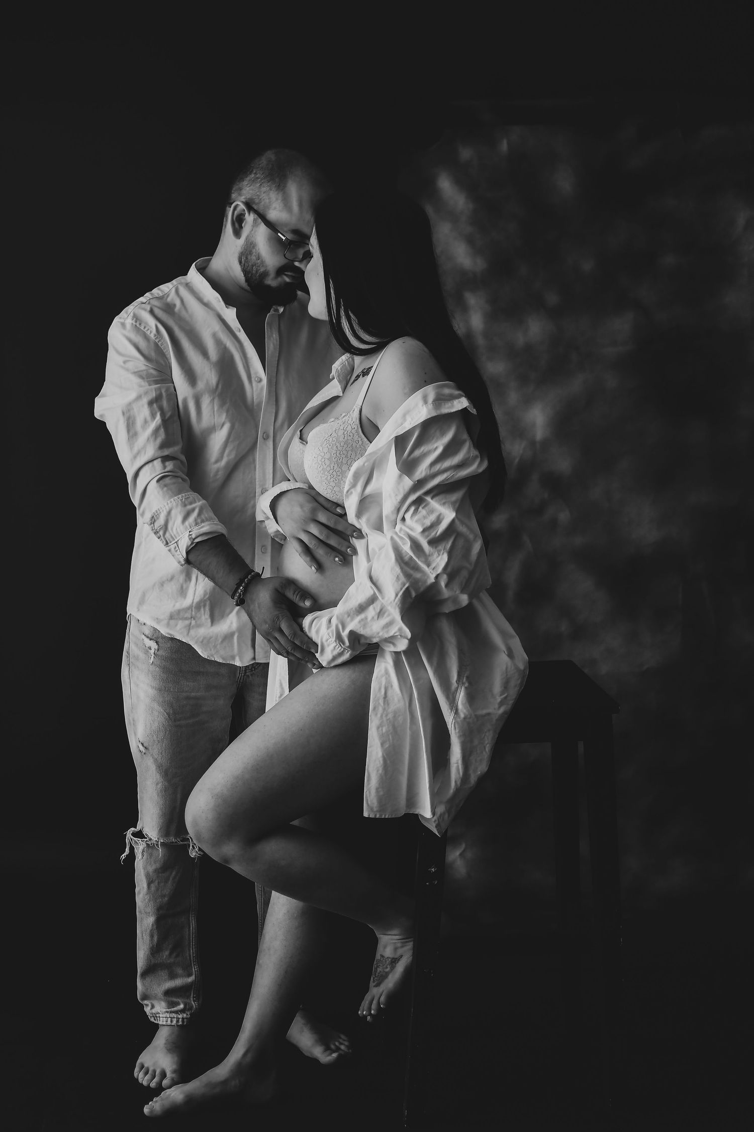 Artistic black and white couples portrait with dramatic lighting and flowing fabric.