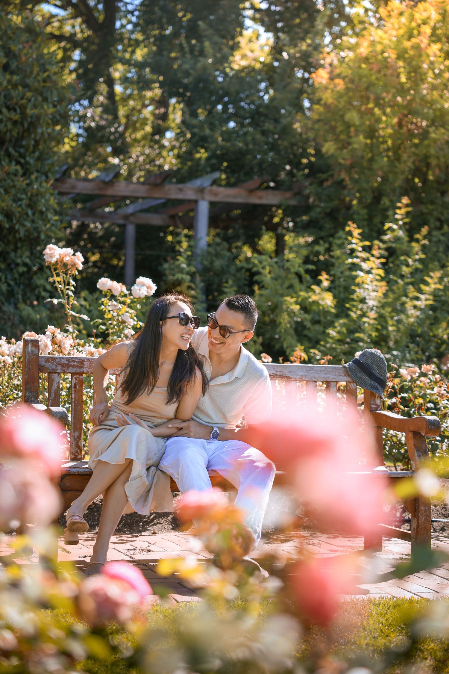 Couple sharing a romantic moment on a garden bench surrounded by blooming roses.