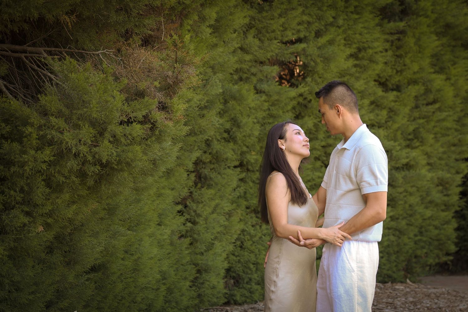 Couple sharing a tender moment against a backdrop of lush green foliage.