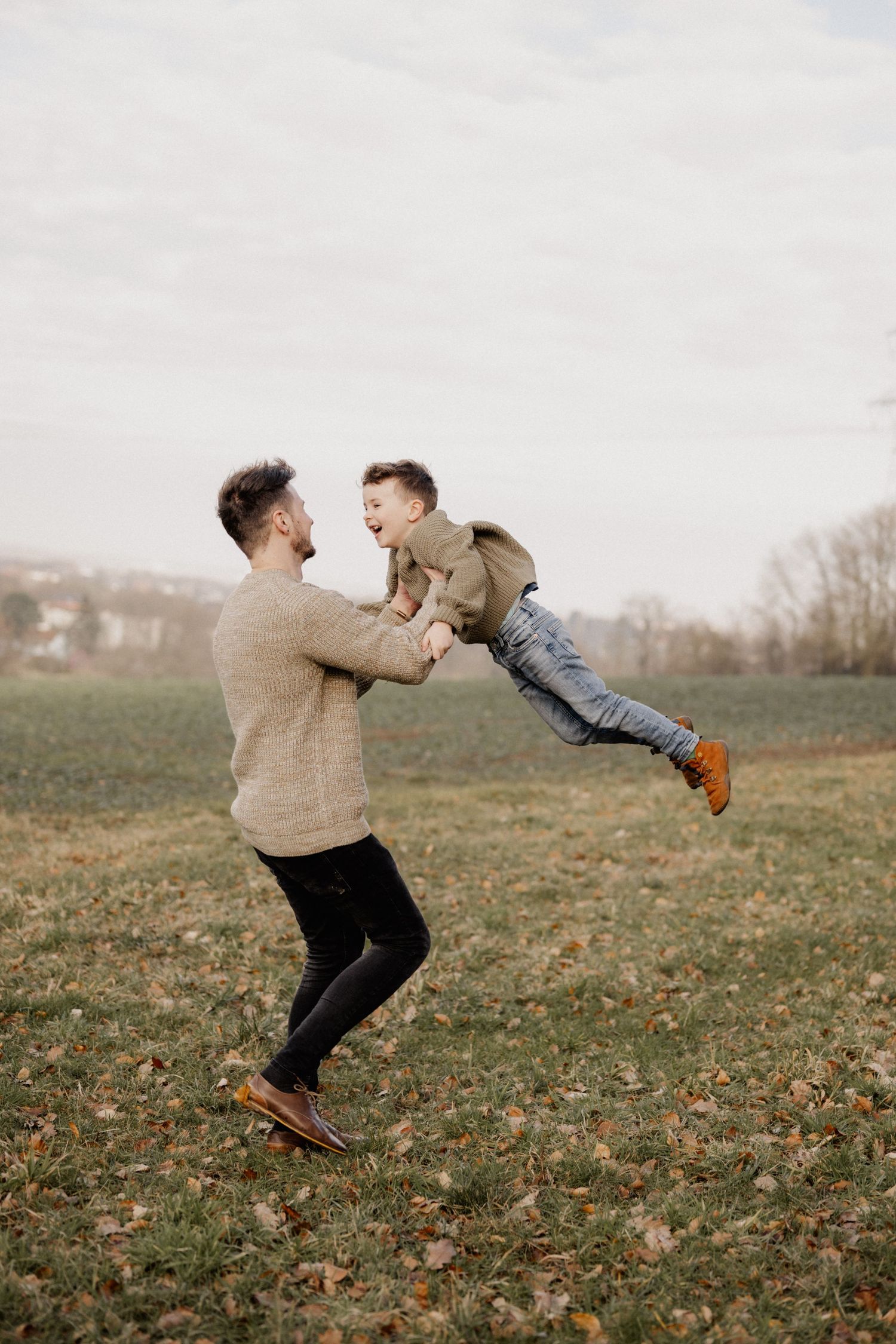 A playful moment captured in a grassy field on an autumn day as two people share a joyful interaction outdoors.