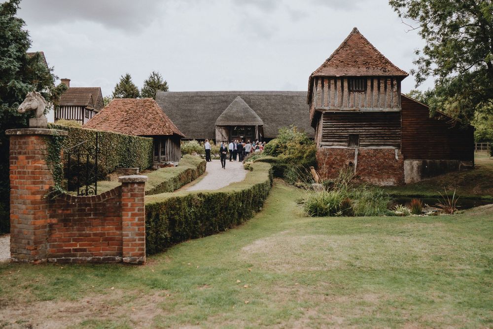 Colville Hall a historic Tudor-style farmstead with brick walls, tiled roofs and tower features surrounded by manicured gardens.