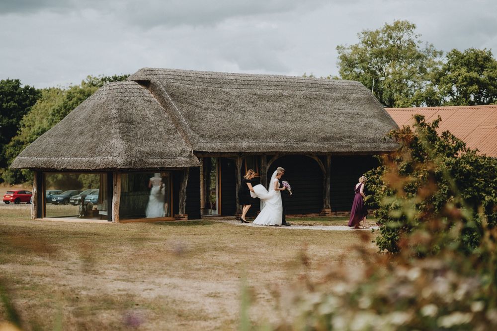 Rustic outdoor wedding ceremony taking place under a traditional thatched roof timber pavilion surrounded by greenery.