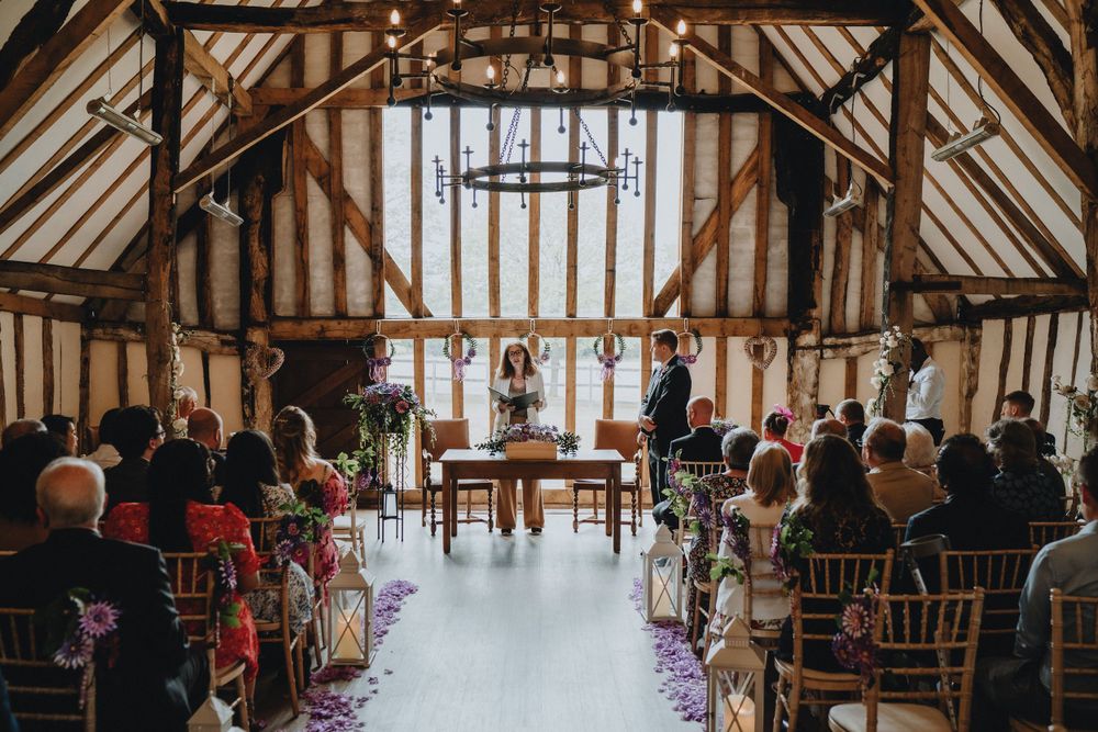 A rustic wooden barn wedding ceremony at Colville Hall setup with rows of guests seated in a traditional indoor venue hall.