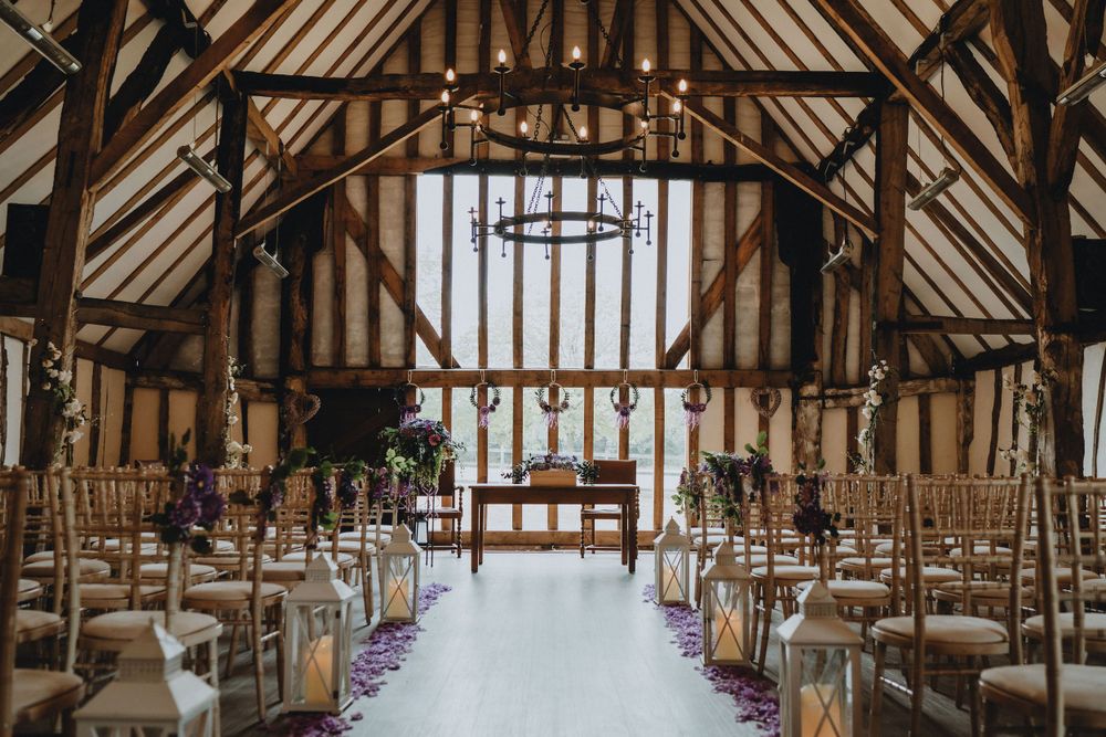 Rustic wooden barn at Colville Hall ainterior set up for a wedding ceremony with rows of chairs and white aisle runner.