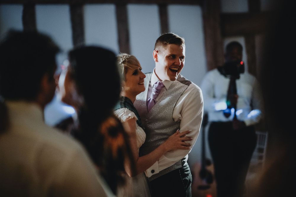 A couple dances together at a wedding reception with guests in the background.
