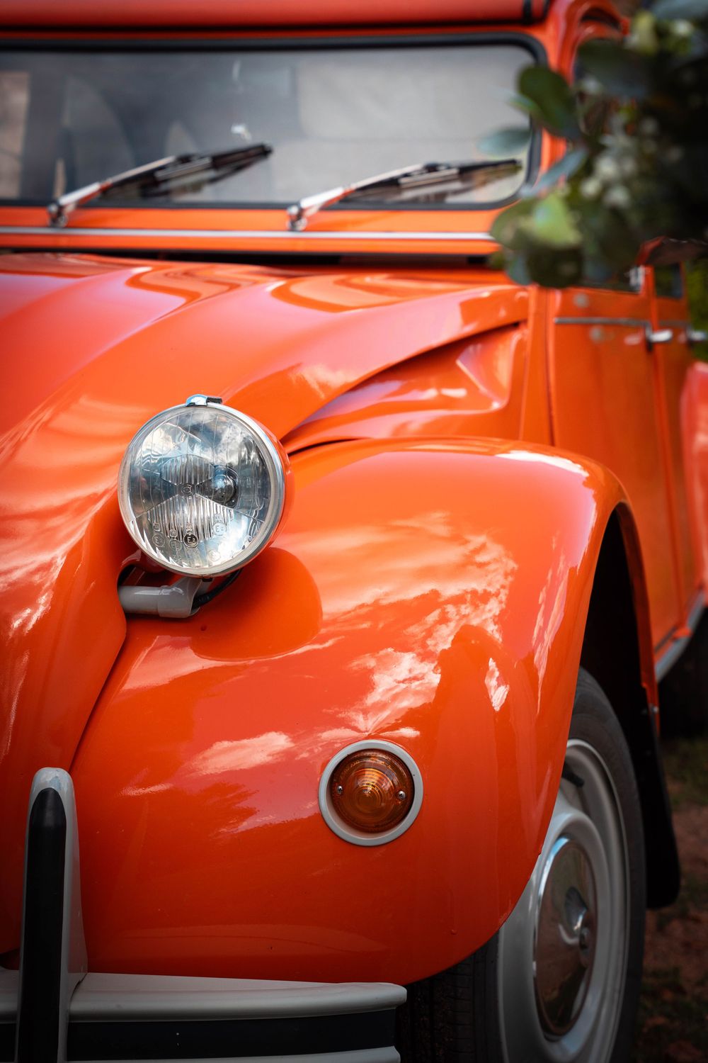 Close-up shots of a vintage orange sports car showing headlight and body panel details in multiple angles.