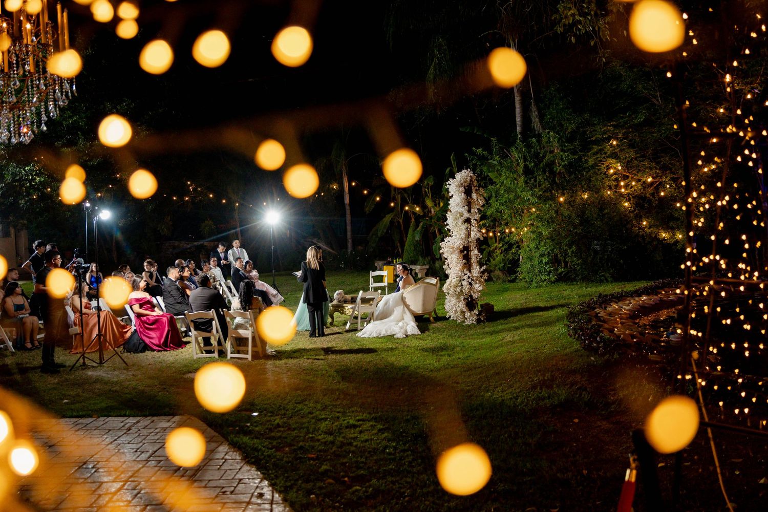 Outdoor evening wedding reception with glowing lanterns and string lights creating a magical atmosphere.