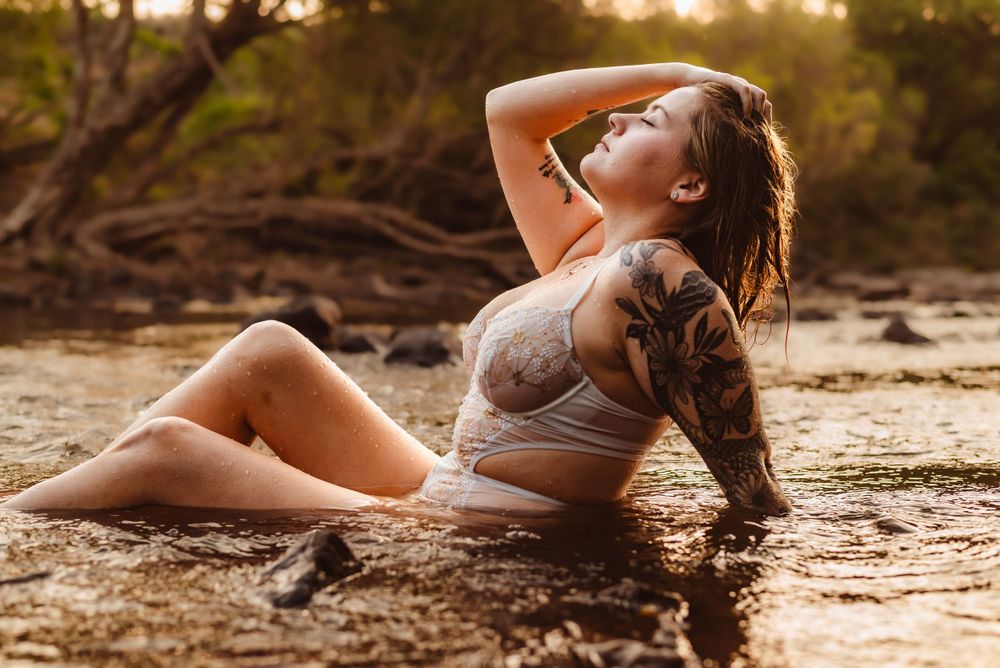 Person in athletic wear posing in shallow water during golden hour.