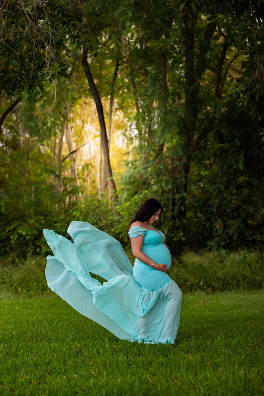 A flowing turquoise dress creates movement in this outdoor maternity photo.