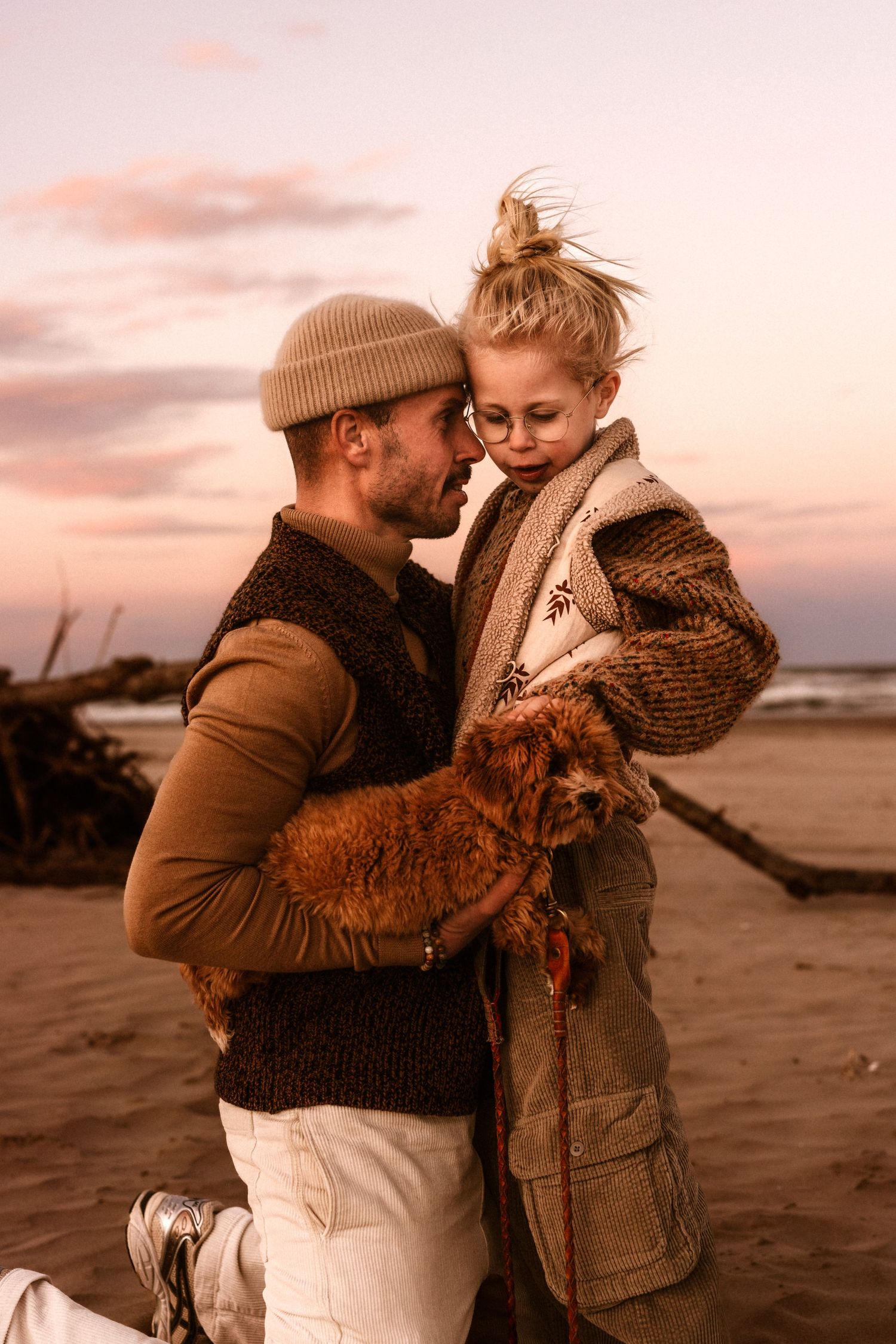 A tender beach scene at sunset in Denia with two people holding an orange cat on a cloudy winter evening - Denia photographer