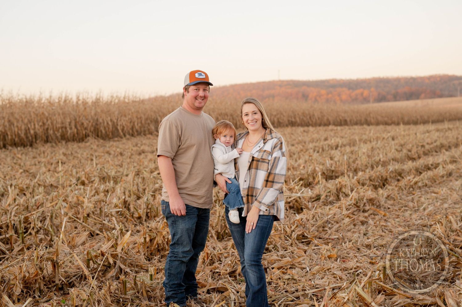Rural family portrait in a harvested cornfield during autumn.