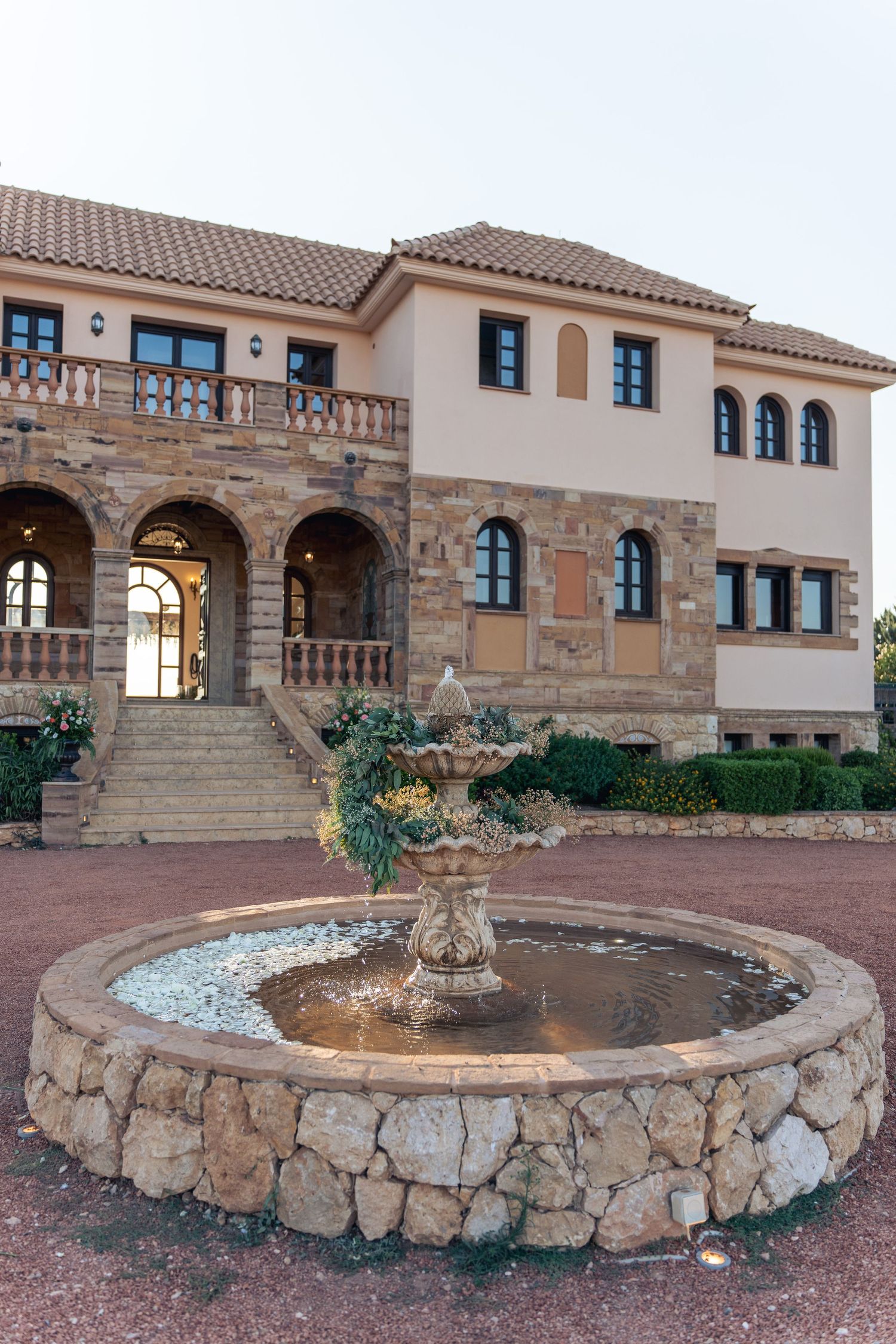 Mediterranean-style villa with stone archways and circular fountain in the courtyard. φωτογραφος βαφτισης χαλκιδα