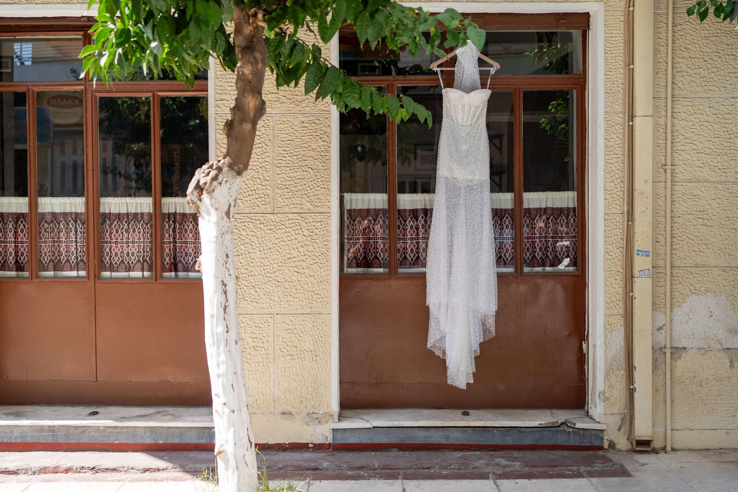 White painted tree trunks line the exterior of a beige building with brown windows.