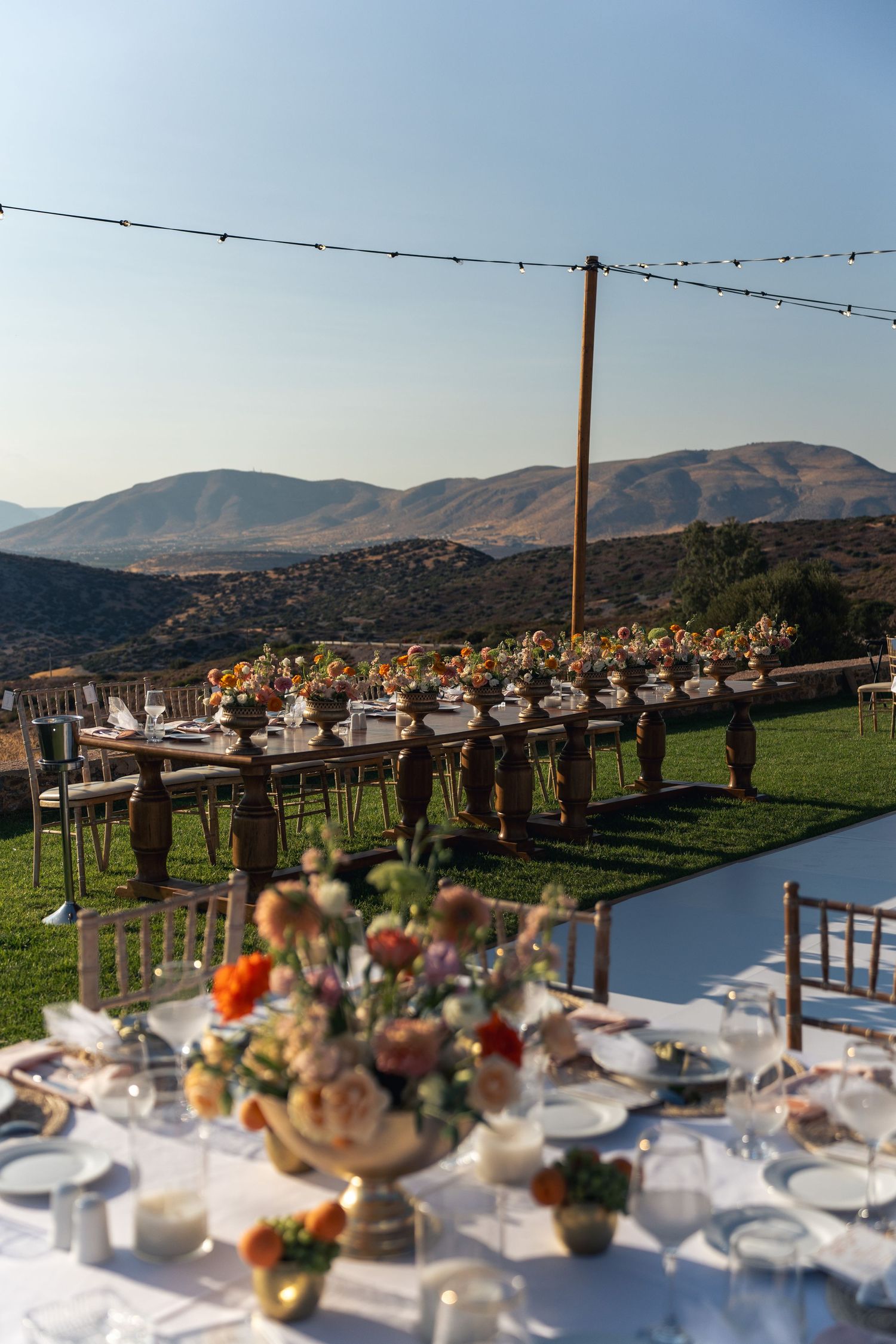 Elegant outdoor wedding reception setup with mountain views and string lights. φωτογράφος βάπτισης Αθήνα