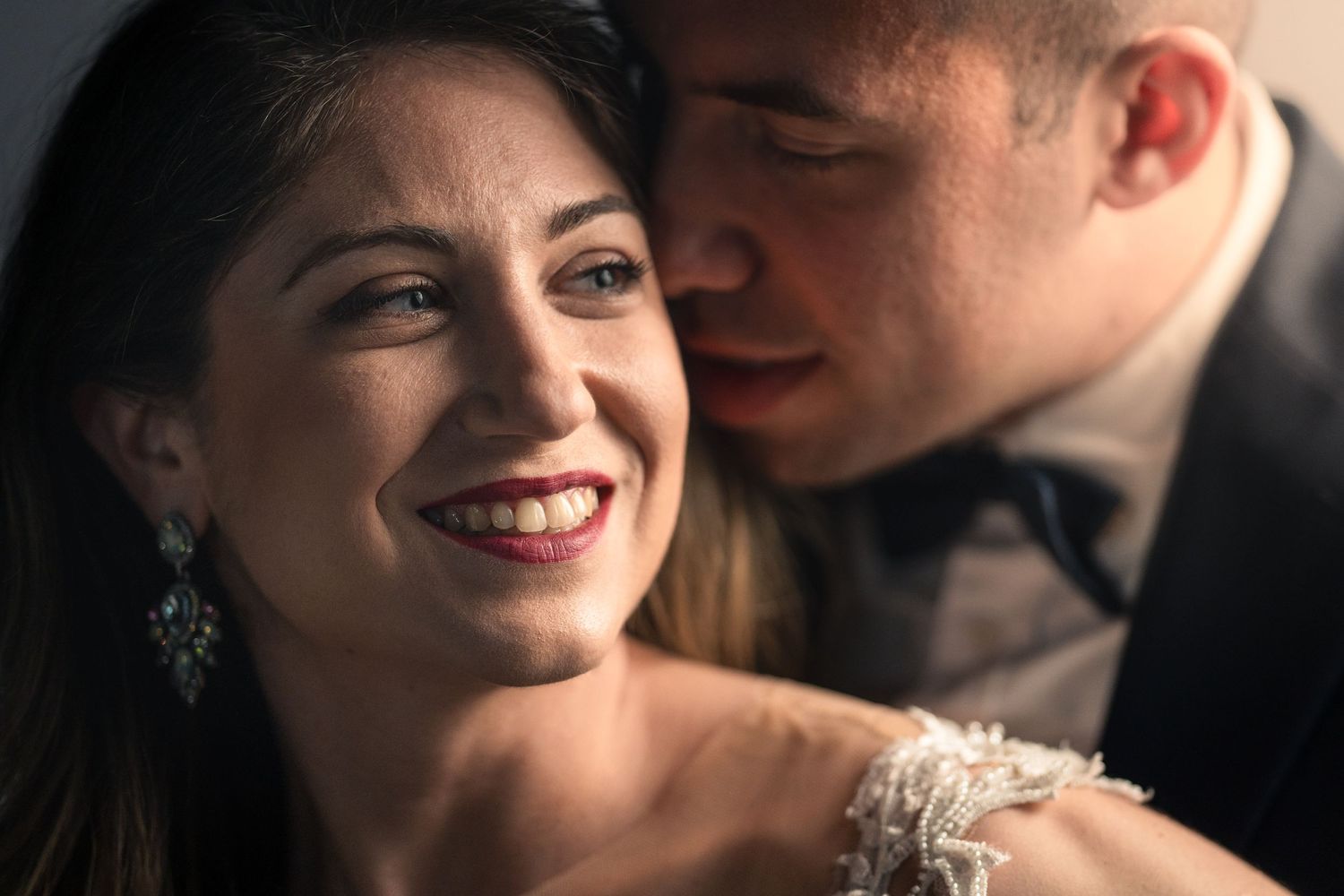 Romantic wedding portrait showing a close embrace with soft lighting and joyful expressions.