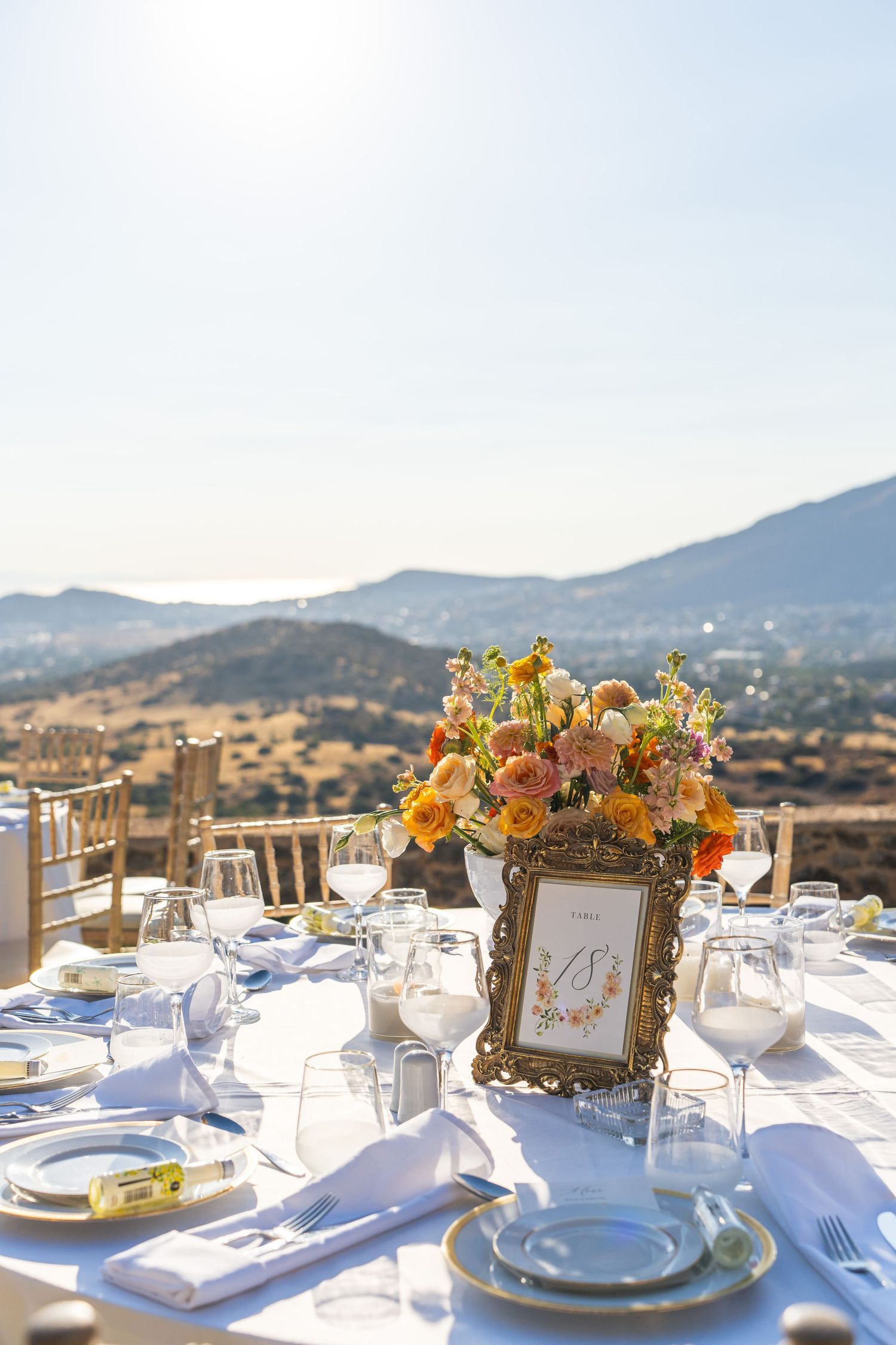 Elegant outdoor wedding table setting with mountain view and floral centerpiece.