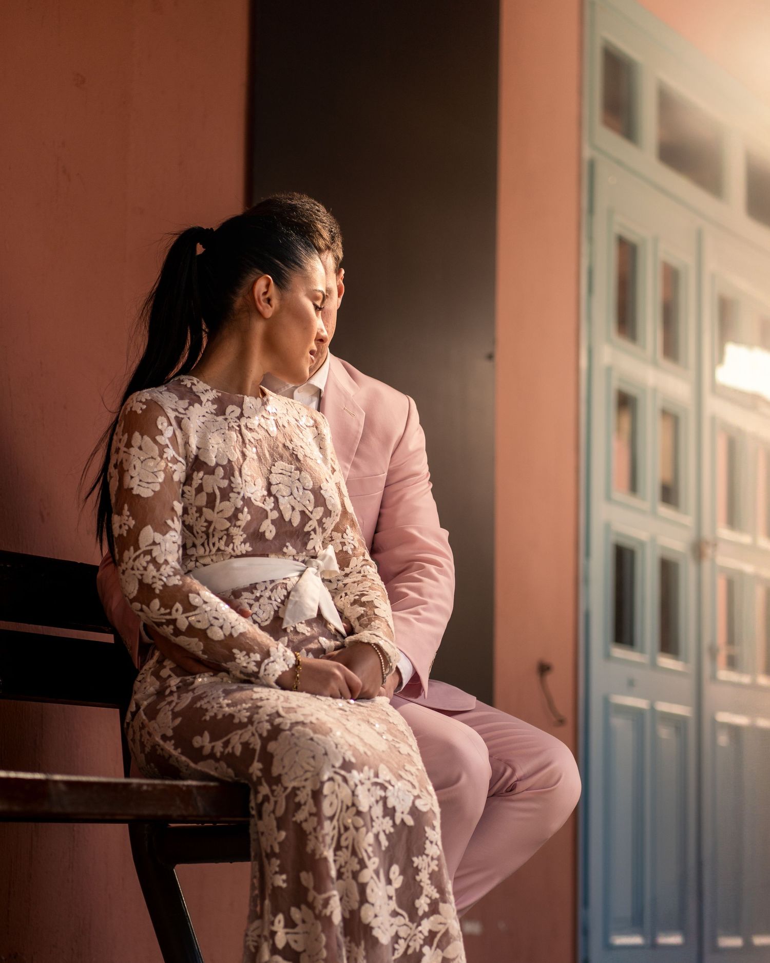 Intimate portrait of couple in matching pink outfits seated on bench.