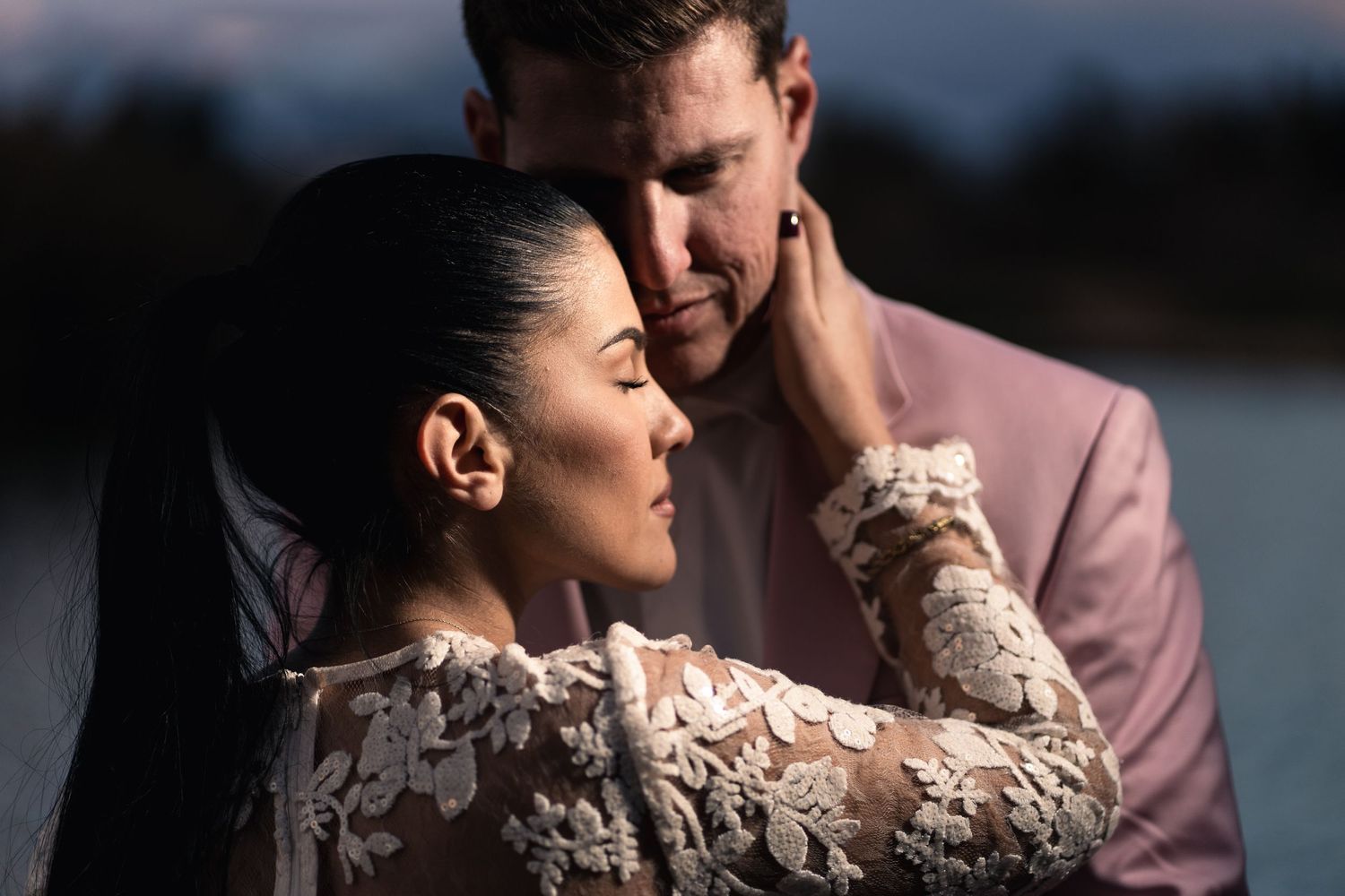 Intimate portrait of couple in evening light by water.